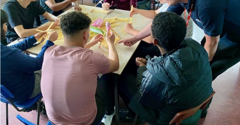 Students participating in a workshop involving building structures using spaghetti and other materials